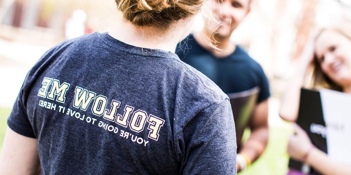 Woman with her back to the camera in a shirt that says, 'Follow Me'.